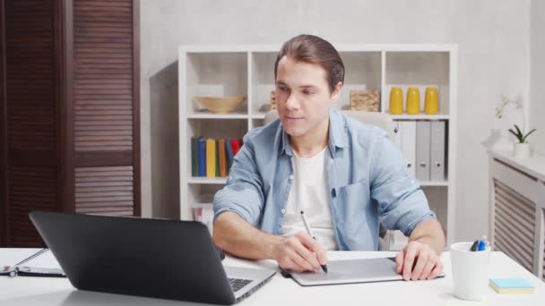 Lieu de travail de designer indépendant au bureau à la maison. Jeune homme travaille à l'aide d'un ordinateur et tablette graphique. Concept d'emploi à distance. — Video