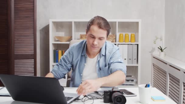 Kancelář fotografa na volné noze. Mladý muž pracuje s počítačem, grafickým tabletem a kamerou. Koncept vzdálené úlohy. — Stock video