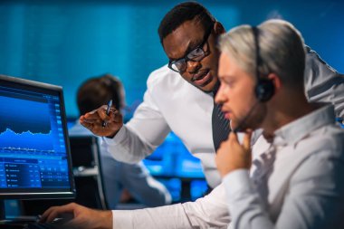 Komisyonculardan oluşan bir ekip, çalışma istasyonu ve analiz teknolojisini kullanarak ofiste çalışıyor. Profesyonel tüccarların işyeri. Küresel finans piyasaları, iş dünyası, döviz kurları ve bankacılık kavramları.