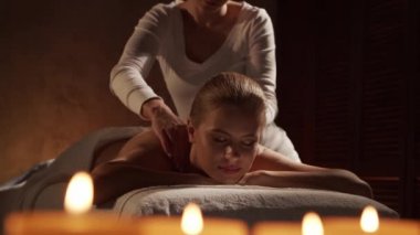 Genç ve güzel bir kadın spa salonunda masaj terapisi görüyor. Sağlıklı yaşam tarzı ve vücut bakımı kavramı.