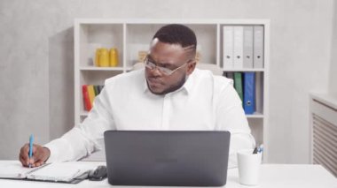 Ev ofisinden bağımsız çalışanların çalıştığı yer. Genç Afro-Amerikalı adam bilgisayar kullanıyor. Uzak görev konsepti.