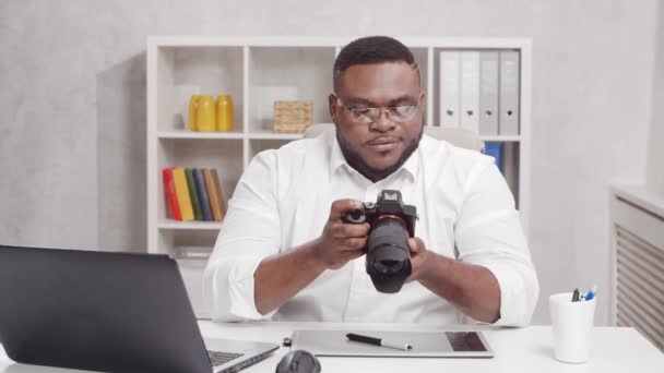 Freelance fotograaf werkplek op kantoor. Jonge Afro-Amerikaanse man werkt met computer, grafische tablet en camera. Afstandswerkconcept. — Stockvideo