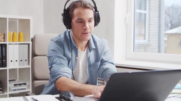 Lugar de trabajo del trabajador independiente o repentino en la oficina en el hogar. El joven trabaja usando la computadora. Concepto de trabajo remoto. — Vídeos de Stock