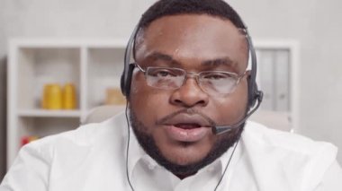 Serbest Çalışan 'ın işyeri. Afro-Amerikalı adam merkez ofiste bilgisayar ve kulaklık kullanarak çalışıyor. Eleman konferans görüşmesi yapıyor. Uzak görev konsepti.