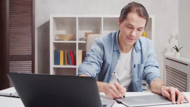 Freelance desainer tempat kerja di kantor rumah. Anak muda bekerja menggunakan komputer dan tablet grafis. Konsep pekerjaan jarak jauh. — Stok Video