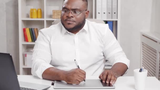 Ev ofisinde serbest tasarımcı işyeri. Genç Afro-Amerikalı bir adam bilgisayar ve grafik tableti kullanıyor. Uzak görev konsepti. — Stok video