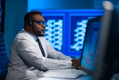 Çağrı merkezi çalışanı müşteriyle kulaklıkla konuşuyor. Afro-Amerikan destek operatörünün işyeri..