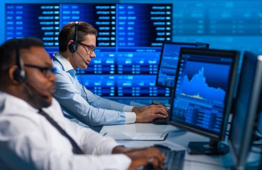 Komisyonculardan oluşan bir ekip, çalışma istasyonu ve analiz teknolojisini kullanarak ofiste çalışıyor. Profesyonel tüccarların işyeri. Küresel finans piyasaları, iş dünyası, döviz kurları ve bankacılık kavramları.