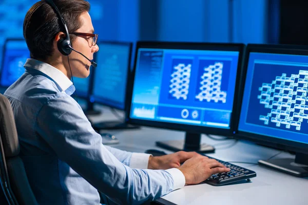 Le préposé du centre d'appels parle avec le client par casque. Lieu de travail de l'opérateur de soutien professionnel au bureau. — Photo