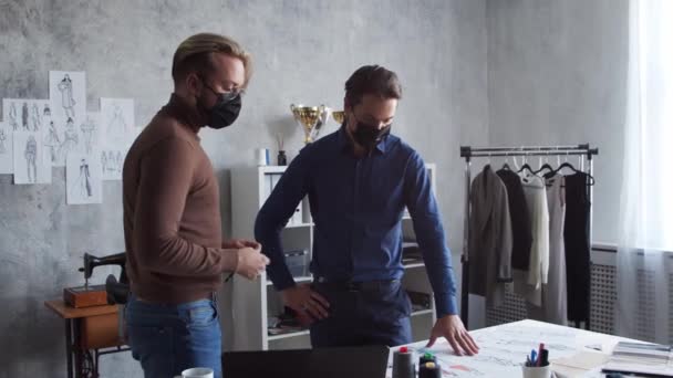 Miejsce pracy młodego i utalentowanego projektanta mody. Krawiec i jego partner biznesowy pracują na stylowym poddaszu używając szkiców ubrań. — Wideo stockowe