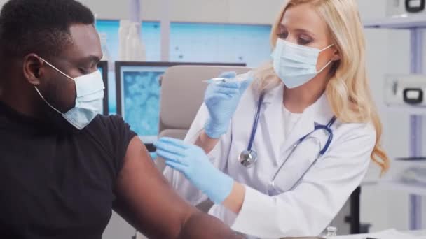 Lekarz robi szczepionkę przeciw koronawirusowi używając strzykawki i igły podskórnej. Profesjonalny pracownik medyczny i pacjent w biurze szpitalnym. Koncepcja szczepień i bezpieczeństwa. — Wideo stockowe