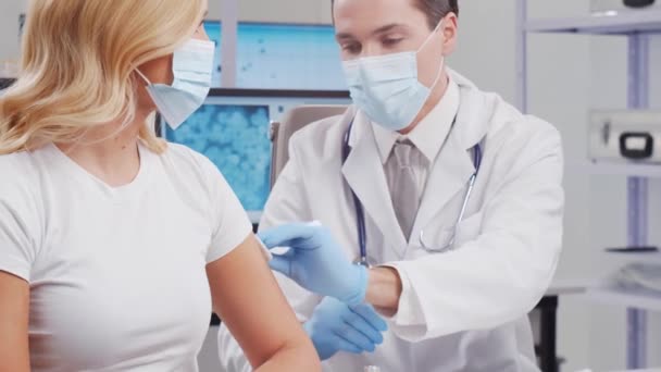 De arts maakt een coronavirusvaccin met een injectiespuit en een injectienaald. Professioneel medisch medewerker en patiënt in het ziekenhuiskantoor. Vaccinatie- en veiligheidsconcept. — Stockvideo