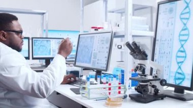 Profesyonel Afro-Amerikan bilim adamı modern bir bilimsel araştırma laboratuvarında aşı üzerinde çalışıyor. Genetik mühendisliği işyeri. Fütürist teknoloji ve bilim konsepti.