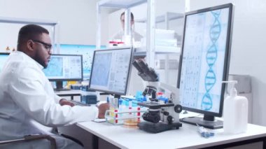 Profesyonel Afro-Amerikan bilim adamı modern bir bilimsel araştırma laboratuvarında aşı üzerinde çalışıyor. Genetik mühendisliği işyeri. Fütürist teknoloji ve bilim konsepti.