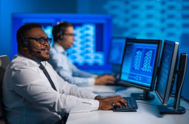 Çağrı merkezi çalışanı müşteriyle kulaklıkla konuşuyor. Afro-Amerikan destek operatörünün işyeri..