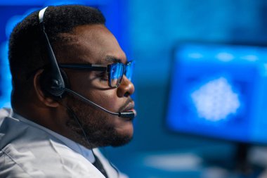 Çağrı merkezi çalışanı müşteriyle kulaklıkla konuşuyor. Afro-Amerikan destek operatörünün işyeri..