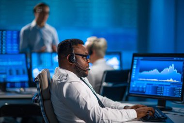 Komisyonculardan oluşan bir ekip, çalışma istasyonu ve analiz teknolojisini kullanarak ofiste çalışıyor. Profesyonel tüccarların işyeri. Küresel finans piyasaları, iş dünyası, döviz kurları ve bankacılık kavramları.