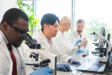 Laboratuvarda çalışan bir bilim adamı. Doktorlar tıbbi araştırma yapıyor. Biyoteknoloji, kimya, bilim, deneyler ve sağlık konsepti. Gün ışığı ve pencere arkaplanı.