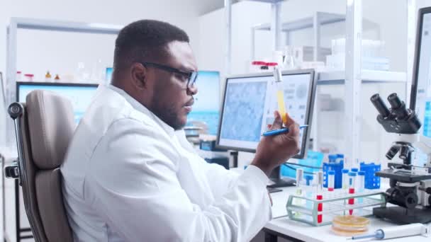 Επαγγελματίας Αφρο-Αμερικανός επιστήμονας εργάζεται πάνω σε ένα εμβόλιο σε ένα σύγχρονο εργαστήριο επιστημονικής έρευνας. Στο χώρο εργασίας των γενετιστών. Μελλοντική έννοια της τεχνολογίας και της επιστήμης. — Αρχείο Βίντεο