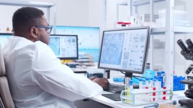Profesyonel Afro-Amerikan bilim adamı modern bir bilimsel araştırma laboratuvarında aşı üzerinde çalışıyor. Genetik mühendisliği işyeri. Fütürist teknoloji ve bilim konsepti.