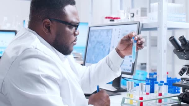 Scienziato afroamericano professionista sta lavorando su un vaccino in un moderno laboratorio di ricerca scientifica. Ingegnere genetico posto di lavoro. Tecnologia futuristica e concetto di scienza. — Video Stock