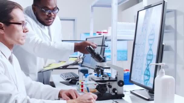 Ein professionelles Wissenschaftlerteam arbeitet in einem modernen wissenschaftlichen Forschungslabor an einem Impfstoff. Gentechniker-Arbeitsplatz. Futuristisches Technologie- und Wissenschaftskonzept. — Stockvideo