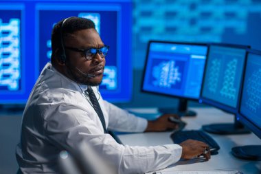 Çağrı merkezi çalışanı müşteriyle kulaklıkla konuşuyor. Afro-Amerikan destek operatörünün işyeri..