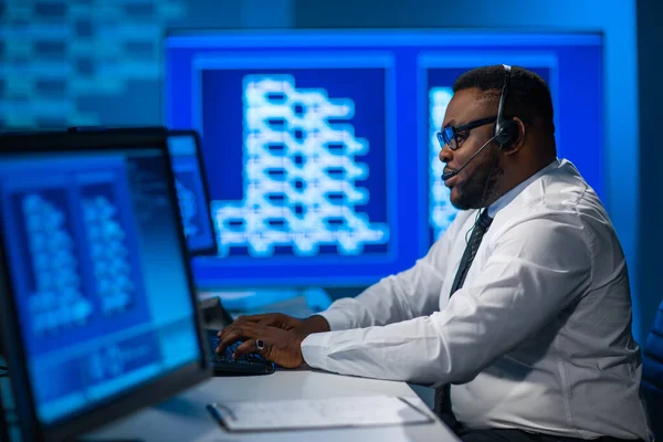 Le préposé du centre d'appels parle avec le client par casque. Lieu de travail de l'opérateur de soutien afro-américain. — Photo