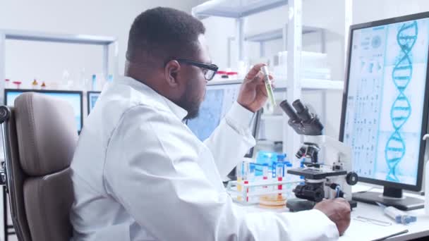 Científico profesional afroamericano está trabajando en una vacuna en un moderno laboratorio de investigación científica. Trabajo de ingeniero genético. Tecnología futurista y concepto de ciencia. — Vídeos de Stock