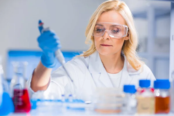 プロの女性科学者は現代の科学研究所でワクチンを研究している。遺伝子工学の職場だ。未来の技術と科学. — ストック写真