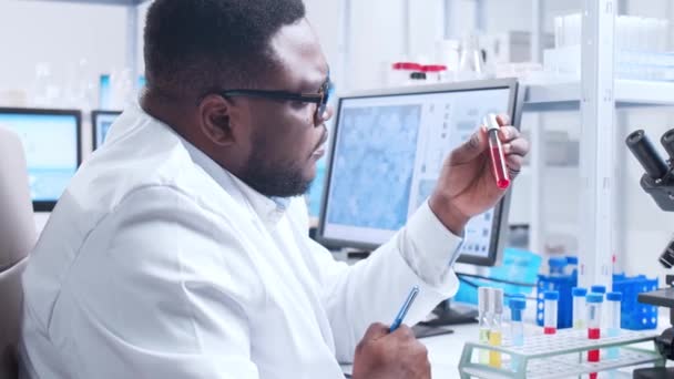 Cientista afro-americano profissional está trabalhando em uma vacina em um laboratório de pesquisa científica moderna. Engenheiro genético no trabalho. Conceito de tecnologia e ciência futurista. — Vídeo de Stock