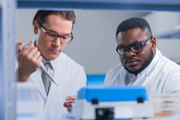 Επαγγελματική ομάδα επιστημόνων εργάζεται πάνω σε ένα εμβόλιο σε ένα σύγχρονο εργαστήριο επιστημονικής έρευνας. Στο χώρο εργασίας των γενετιστών. Μελλοντική τεχνολογία και επιστήμη. — Φωτογραφία Αρχείου