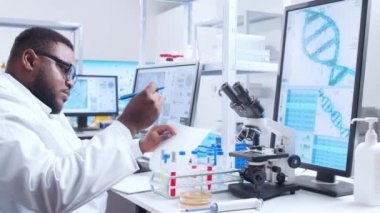 Profesyonel Afro-Amerikan bilim adamı modern bir bilimsel araştırma laboratuvarında aşı üzerinde çalışıyor. Genetik mühendisliği işyeri. Fütürist teknoloji ve bilim konsepti.