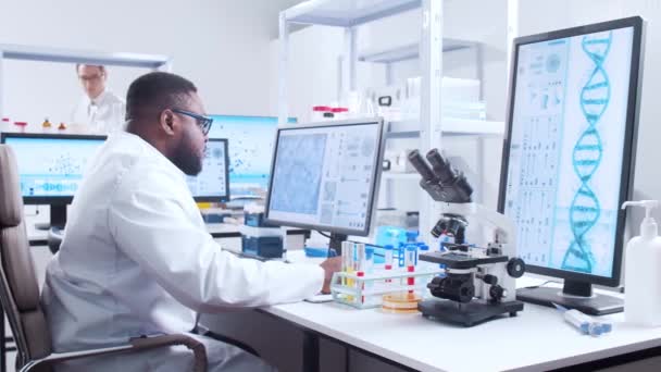 Professionele Afro-Amerikaanse wetenschapper werkt aan een vaccin in een modern wetenschappelijk onderzoekslaboratorium. Genetische ingenieur werkplek. Futuristische technologie en wetenschapsconcept. — Stockvideo