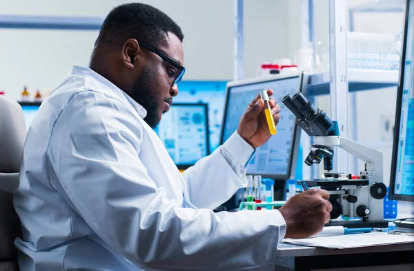 Cientista afro-americano profissional está trabalhando em uma vacina em um laboratório de pesquisa científica moderna. Engenheiro genético no trabalho. Tecnologia e ciência futuras. — Fotografia de Stock