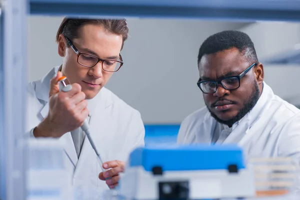 Επαγγελματική ομάδα επιστημόνων εργάζεται πάνω σε ένα εμβόλιο σε ένα σύγχρονο εργαστήριο επιστημονικής έρευνας. Στο χώρο εργασίας των γενετιστών. Μελλοντική τεχνολογία και επιστήμη. — Φωτογραφία Αρχείου