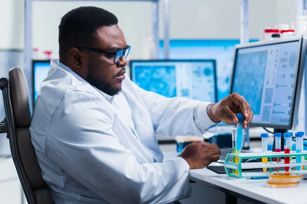 Cientista afro-americano profissional está trabalhando em uma vacina em um laboratório de pesquisa científica moderna. Engenheiro genético no trabalho. Tecnologia e ciência futuras. — Fotografia de Stock