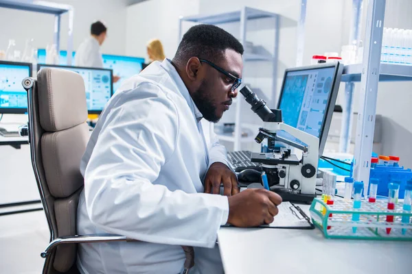 Un scientifique afro-américain professionnel travaille sur un vaccin dans un laboratoire de recherche scientifique moderne. Ingénieur génétique lieu de travail. Technologies et sciences futures. — Photo