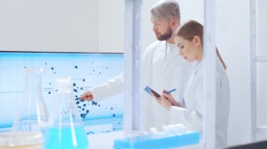 Profesyonel bilim adamları modern bir bilimsel araştırma laboratuvarında bir aşı üzerinde çalışıyorlar. Genetik mühendisliği işyeri. Gelecekteki teknoloji ve bilim.