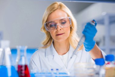 Profesyonel kadın bilim adamı modern bir bilimsel araştırma laboratuvarında aşı üzerinde çalışıyor. Genetik mühendisliği işyeri. Gelecekteki teknoloji ve bilim.