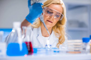 Profesyonel kadın bilim adamı modern bir bilimsel araştırma laboratuvarında aşı üzerinde çalışıyor. Genetik mühendisliği işyeri. Gelecekteki teknoloji ve bilim.