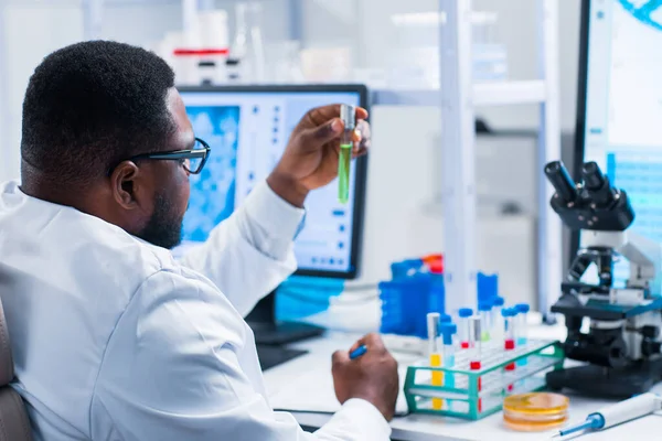 Professional African-American scientist is working on a vaccine in a modern scientific research laboratory. Genetic engineer workplace. Future technology and science.