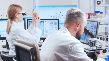 Profesyonel bilim adamları modern bir bilimsel araştırma laboratuvarında bir aşı üzerinde çalışıyorlar. Genetik mühendisliği işyeri. Gelecekteki teknoloji ve bilim.