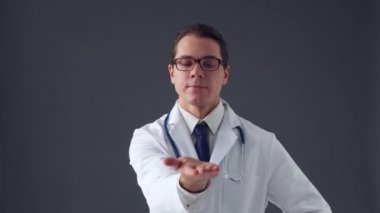 Gri arkaplan üzerinde görünmez görüntüleme arayüzleri üzerinde çalışan genç profesyonel tıp doktorunun stüdyo portresi