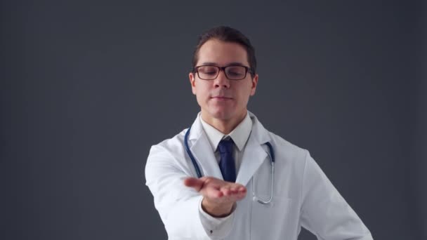 Retrato de estudio de un joven médico profesional que trabaja con interfaces digitales de imágenes invisibles sobre fondo gris — Vídeos de Stock