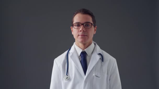 Retrato de estudio de un joven médico profesional que trabaja con interfaces digitales de imágenes invisibles sobre fondo gris — Vídeo de stock