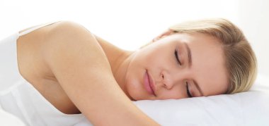 Genç ve güzel sarışın kadın yatakta. Sabah güneşinin altında uyuyan kadın. Sağlık ve dinlenme kavramı.