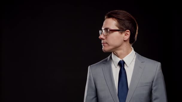 Studio portret odnoszącego sukcesy i mądrego biznesmena w garniturze i krawacie. Mężczyzna w formalnym stroju na czarnym tle. — Wideo stockowe