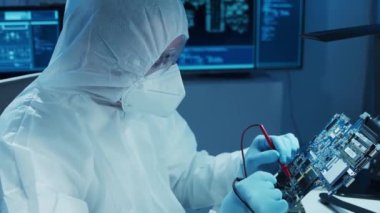 Mikro elektronik mühendisi, bilgisayar sistemleri ve mikroişlemciler üzerine modern bir bilim laboratuvarında çalışıyor. Elektronik fabrika işçisi ana kartı test ediyor ve yazılımı kodluyor..