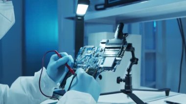 Mikro elektronik mühendisi, bilgisayar sistemleri ve mikroişlemciler üzerine modern bir bilim laboratuvarında çalışıyor. Elektronik fabrika işçisi ana kartı test ediyor ve yazılımı kodluyor..